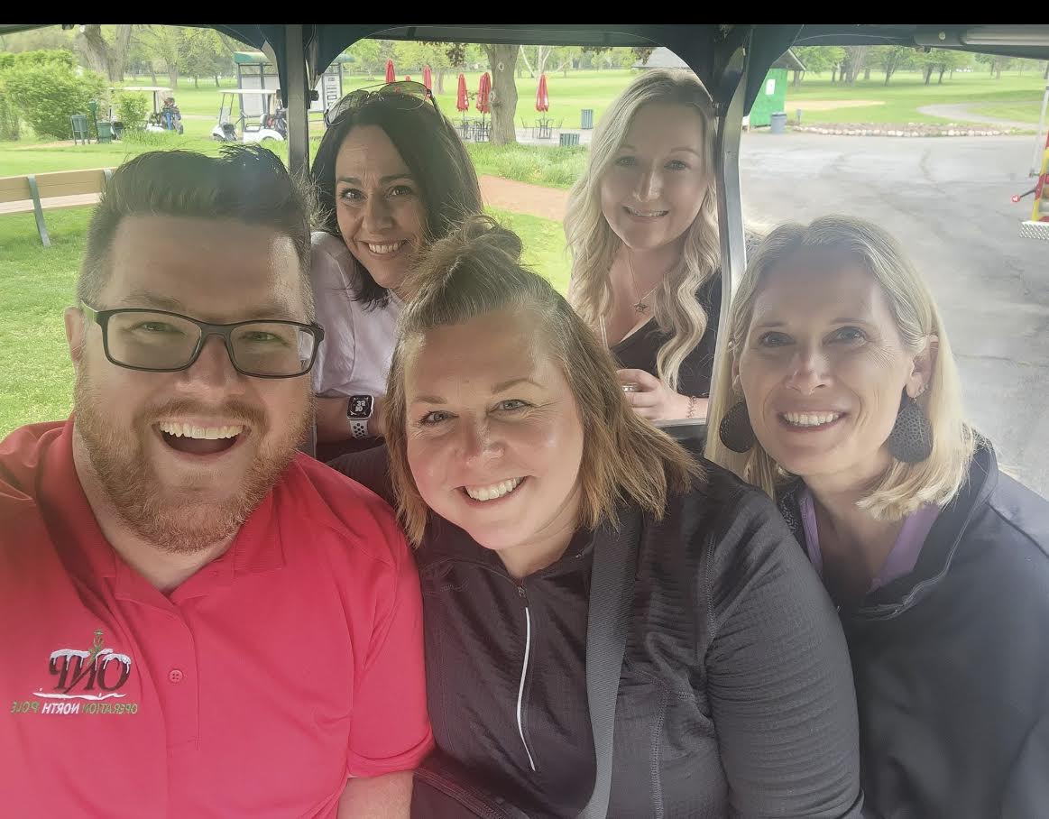 Volunteer team riding together in a golf cart at an Operation North Pole event