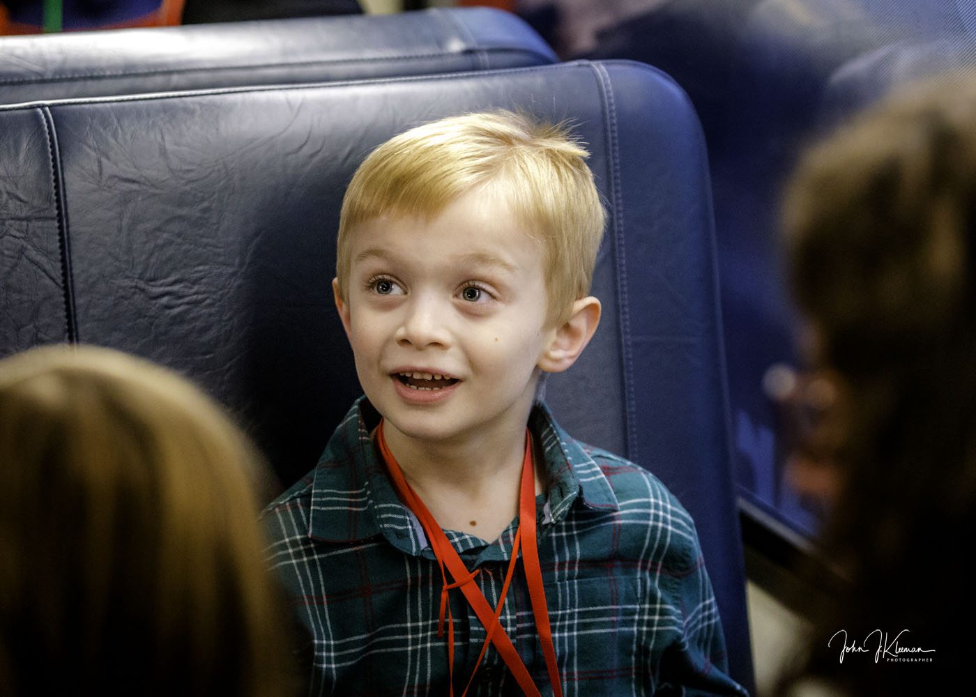 A wide-eyed young boy in a plaid shirt aboard the train