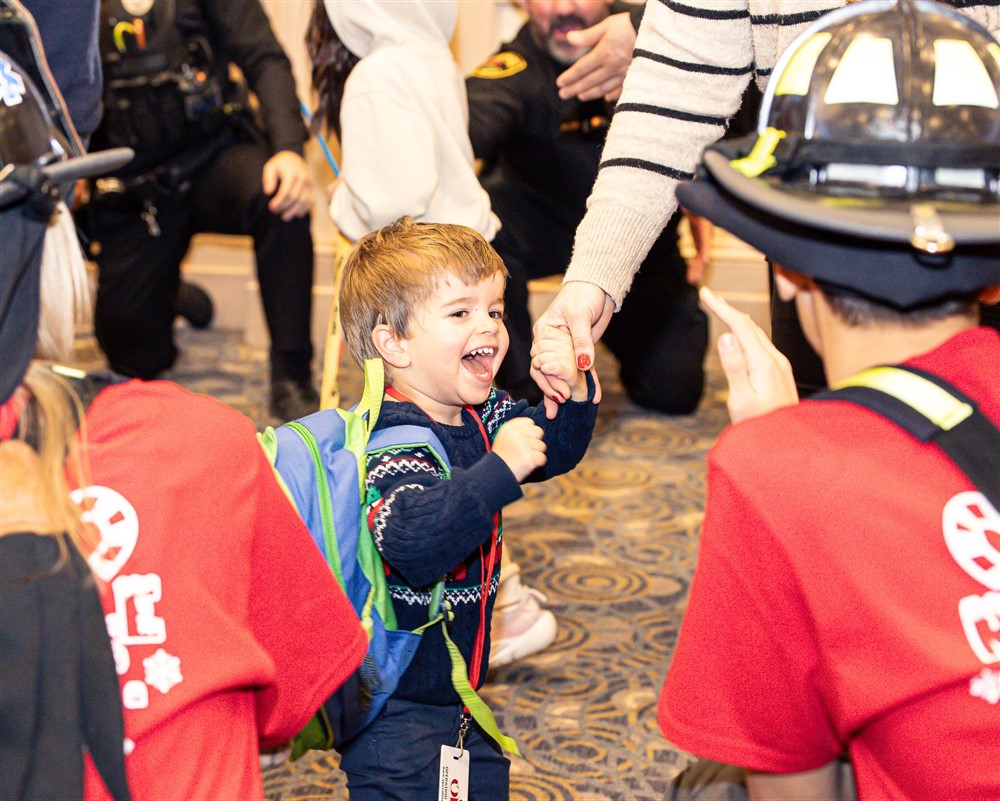 A joyful boy high-fiving a volunteer through a tunnel of firefighters and police officers