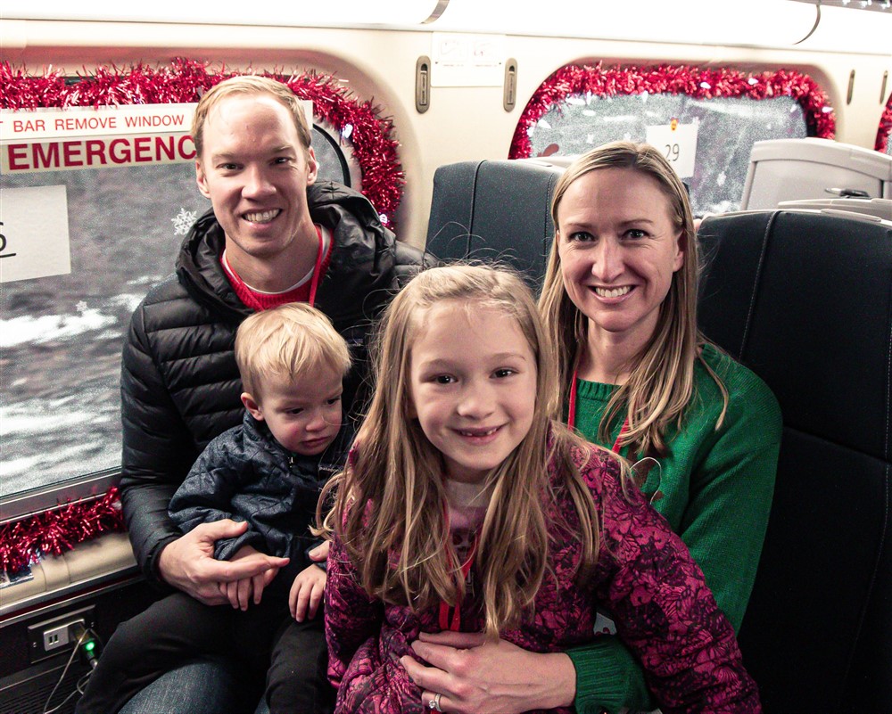 A smiling family of four aboard the Operation North Pole train