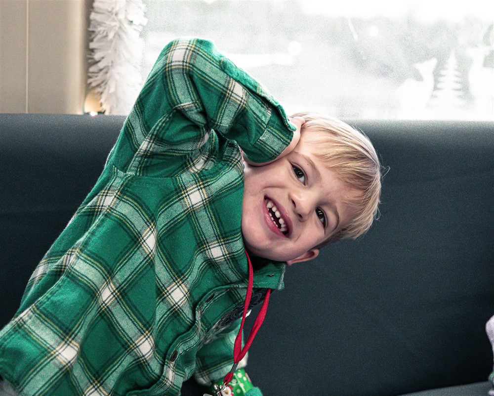 A smiling boy in a green plaid shirt at Operation North Pole