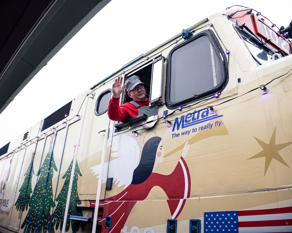 Metra train conductor waving from the cab of the Operation North Pole holiday train