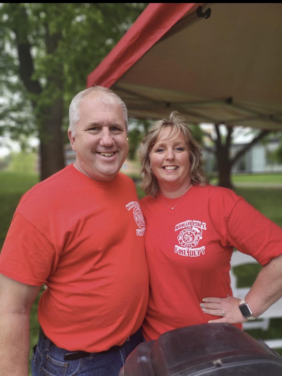 Two Operation North Pole volunteers in green Fire Dept hoodies smiling together